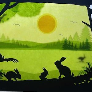 May include: Silhouettes of rabbits in a woodland scene with a bright yellow sun in the sky. The rabbits are black and the woodland is green.