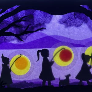 Könnte beinhalten: Eine hinterleuchtete Scherenschnittszene aus Papier mit den Silhouetten von drei Kindern und einem kleinen Hund, die durch eine Landschaft gehen. Die Kinder tragen Laternen an Stöcken mit gelben, roten und grünen kreisförmigen Lichtern.