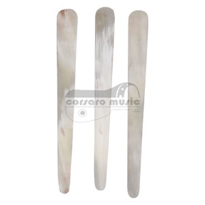 May include: Three white bone guitar picks, each with a slightly different shape and texture.