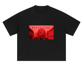 Könnte beinhalten: Ein schwarzes T-Shirt mit kurzen Ärmeln und einem rechteckigen Grafikdruck in der Mitte. Die Grafik zeigt ein rot getöntes Bild einer Person mit den Händen im Gesicht, wobei der Text POSSESSOR in schwarzen Buchstaben darüber steht.