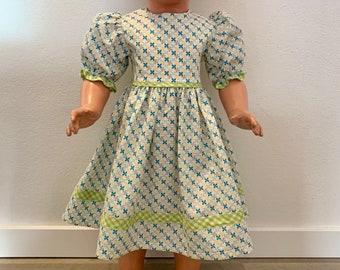 Fröhliches, selbstgenähtes Puppenkleidchen mit buntem Muster für Schildkröt-Puppe, Gr. 56-70