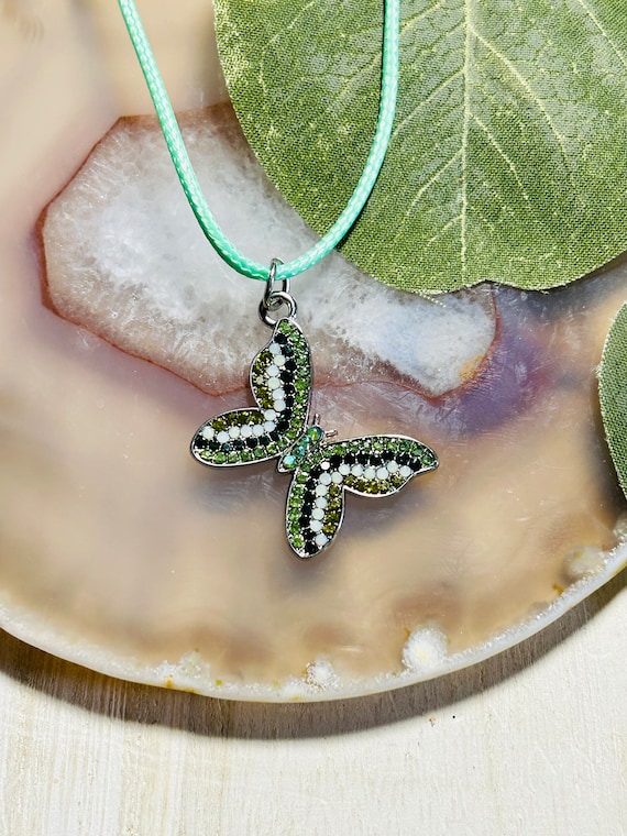 Premium Photo | A gold butterfly necklace with green and gold stones and a  green diamond.