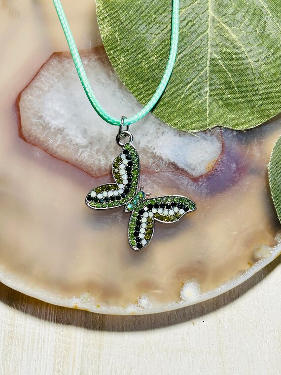 Premium Photo | A gold butterfly necklace with green and gold stones and a  green diamond.