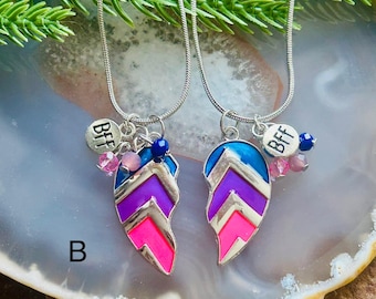 May include: Two silver necklaces, each with a pendant shaped like a feather, designed to fit together. The pendants are in pink, purple, and blue. Each has a "BFF" charm.