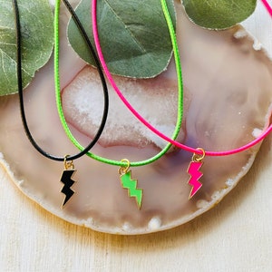May include: Three necklaces with lightning bolt charms. The necklaces are black, green, and pink.