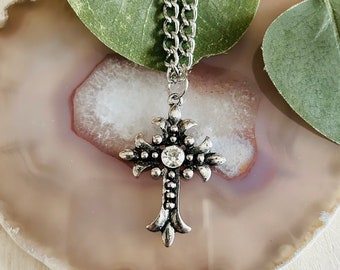 Colar feminino com pingente de cruz e gema prateada.