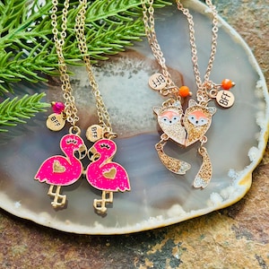 May include: Two gold-tone necklaces with matching pendants. One pair features pink flamingo pendants with heart details, and the other has fox pendants. Each necklace has a small charm that says "BFF".