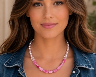 May include: A beaded necklace featuring a sequence of light pink pearls, clear faceted glass beads, and rectangular pink marbled stones. The necklace is arranged with the marbled stones at the center, flanked by clear beads and rows of pearls.
