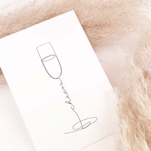 May include: A simple line drawing of a champagne flute with the word "cheers" written in cursive below it. The drawing is on a white background.