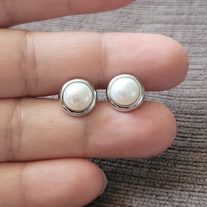 Peut inclure: Une paire de boucles d'oreilles en argent avec des accents de perles blanches.
