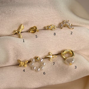 May include: Ten gold and pearl earrings displayed on a cream-colored fabric background. The earrings are numbered 1 through 8.