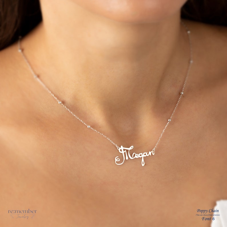 Sterling silver custom name necklace with Megan in an elegant cursive font, displayed on a model wearing a delicate poppy chain with small bead accents. Personalized jewelry, ideal for gifts or daily wear, customizable with different names and fonts