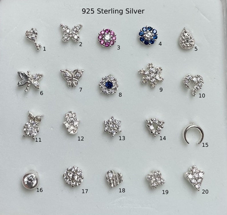 May include: Twenty different 925 sterling silver nose rings with various designs, including butterflies, flowers, stars, and moons. Each ring is adorned with sparkling cubic zirconia stones.