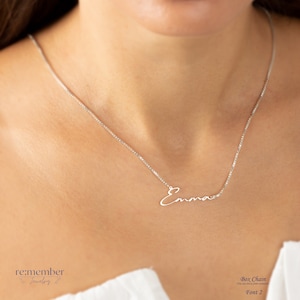 Sterling silver custom name necklace with Emma in a delicate cursive font, showcased on a model wearing a fine box chain. Elegant and personalized jewelry, perfect for gifts or daily wear, customizable with different names and font styles.