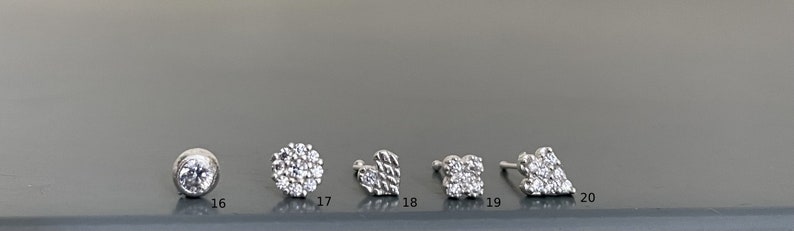May include: A set of ten silver-toned earrings with various crystal designs. The earrings are numbered 16 through 20.