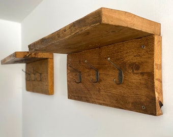 May include: Rustic wooden shelf with three hooks, perfect for hanging coats, hats, or bags. The shelf is made of reclaimed wood and has a natural, distressed finish.