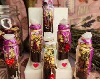 May include: Six small glass bottles filled with various herbs, crystals, and charms. Each bottle is topped with a clear quartz crystal and sealed with a pink wax seal. The bottles are arranged on a white surface.