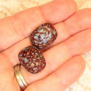 May include: Two brown and blue speckled ceramic beads with gold flecks.