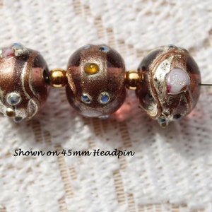 May include: Three brown glass beads with gold and silver accents. The beads are decorated with swirls and dots of blue, white, and gold. The beads are shown on a 45mm headpin. Shown on 45mm Headpin.