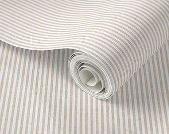 May include: A roll of peel and stick wallpaper with vertical stripes in alternating beige and white. The text "Peel & stick" is in the upper left corner. The wallpaper is partially unrolled, revealing the rolled-up portion.