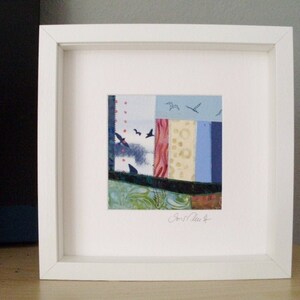 Peut inclure: Une &oelig;uvre d'art encadr&eacute;e de blanc pr&eacute;sentant un collage abstrait color&eacute; de chutes de tissu avec un ciel bleu et des oiseaux. L'&oelig;uvre est sign&eacute;e "Lori Clark" en bas &agrave; droite.