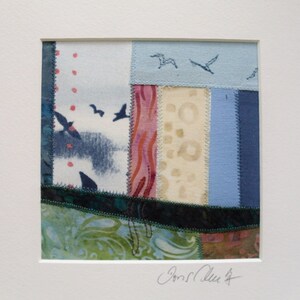Peut inclure: Une petite courtepointe patchwork encadr&eacute;e avec une vari&eacute;t&eacute; de tissus dans des tons de bleu, vert, rose et beige. La courtepointe est compos&eacute;e de diff&eacute;rentes formes et tailles de tissus et pr&eacute;sente un motif d'oiseaux volant dans le ciel. La courtepointe est sign&eacute;e "Joan Klee" dans le coin inf&eacute;rieur droit.