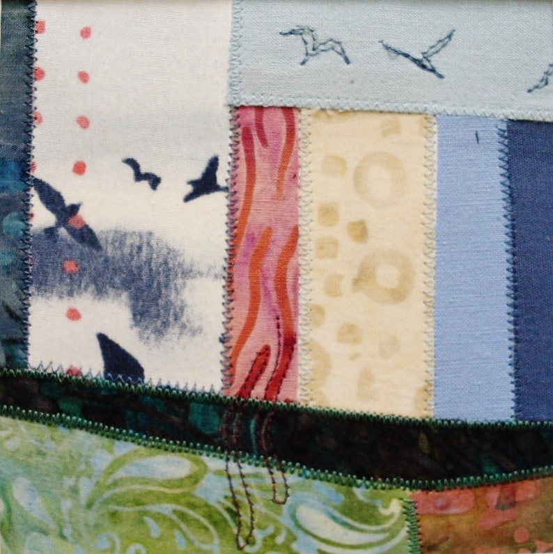 Peut inclure: Une courtepointe en patchwork avec une vari&eacute;t&eacute; de tissus dans des tons de bleu, vert, rose et blanc. La courtepointe est compos&eacute;e de carr&eacute;s et de rectangles de diff&eacute;rentes tailles, et les coutures sont visibles. La courtepointe est d&eacute;cor&eacute;e d'oiseaux brod&eacute;s.