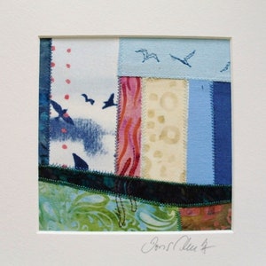 Peut inclure: Une petite &oelig;uvre d'art en tissu encadr&eacute;e avec un motif de patchwork. Le tissu est dans des tons de bleu, vert, rose et blanc. De petits oiseaux bleus sont brod&eacute;s sur le tissu. La pi&egrave;ce est sign&eacute;e "Jonell Allen".