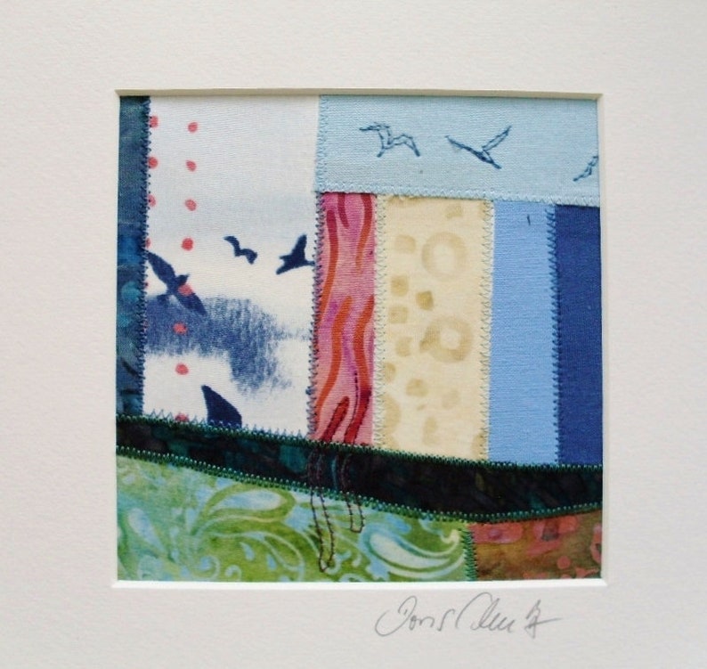 Peut inclure: Une petite &oelig;uvre d'art en tissu encadr&eacute;e avec un motif de patchwork. Le tissu est dans des tons de bleu, vert, rose et blanc. De petits oiseaux bleus sont brod&eacute;s sur le tissu. La pi&egrave;ce est sign&eacute;e "Jonell Allen".