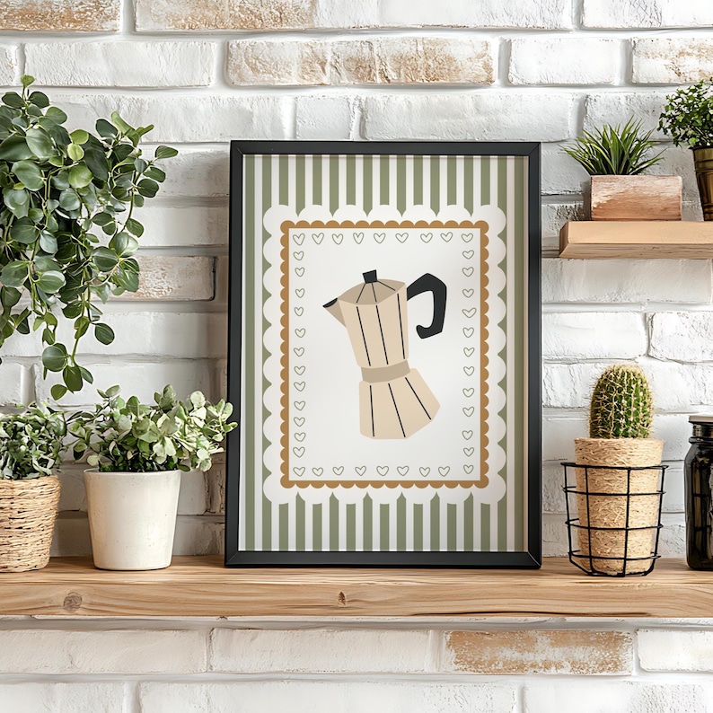 Peut inclure: Impression encadr&eacute;e avec une illustration de cafeti&egrave;re. L'&oelig;uvre a un fond blanc avec une bordure marron de c&oelig;urs et un fond &agrave; rayures vertes et blanches. La cafeti&egrave;re est beige et noire.