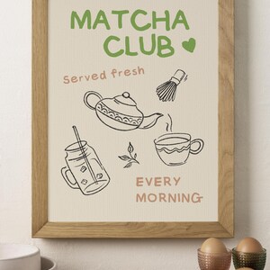 Pu&ograve; includere: Una stampa incorniciata con le parole "Matcha Club" in verde, e "served fresh" e "every morning" in rosa. La stampa presenta disegni a tratto della preparazione del t&egrave; matcha: una teiera, una frusta, una tazza e matcha freddo. La cornice &egrave; marrone chiaro.