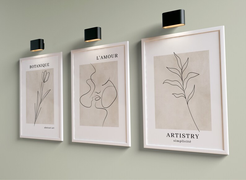 K&ouml;nnte beinhalten: Drei gerahmte minimalistische Linienkunst-Drucke mit wei&szlig;en Rahmen und beigefarbenem Hintergrund. Die Drucke zeigen eine einzeilige Zeichnung einer Blume, eines Gesichts und eines Blattes. Die Drucke sind mit "Botanique", "L'Amour" und "Artistry Simplicit&eacute;" betitelt.