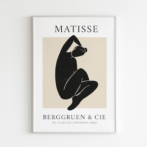 May include: A black and white minimalist art print featuring a stylized figure in a seated pose. The print has the text "MATISSE" at the top and "BERGGRUEN & CIE NO. 70, RUE DE L'UNIVERSITE, PARIS" at the bottom.