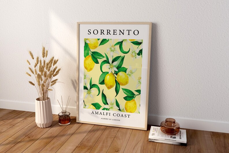 May include: A framed print with a yellow background and a pattern of green leaves, white flowers, and yellow lemons. The print says "SORRENTO AMALFI COAST ALBERO DI LIMONE".