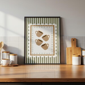 May include: A framed print featuring four brown coffee cups on a white background with a scalloped edge and heart accents. The background has vertical green and white stripes. The print is displayed on a wooden surface.