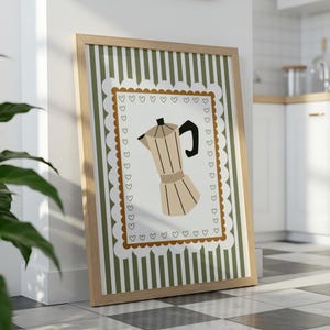 Peut inclure: Une affiche encadr&eacute;e repr&eacute;sentant une cafeti&egrave;re. L'&oelig;uvre a un cadre en bois brun clair et un fond blanc avec un motif &agrave; rayures vertes. La cafeti&egrave;re est beige avec une poign&eacute;e et un dessus noirs.