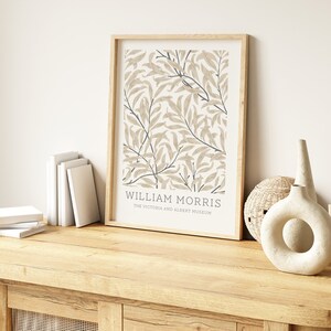 May include: A framed print of a botanical illustration with a beige background and blue accents. The print features the text "William Morris" and "The Victoria and Albert Museum".