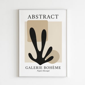 May include: A framed print with the text "ABSTRACT" and "GALERIE BOHEME" in black text on a beige background. The print features a black abstract shape resembling a plant with brown geometric shapes behind it. The text "Papier Decoup&eacute;" is also included.