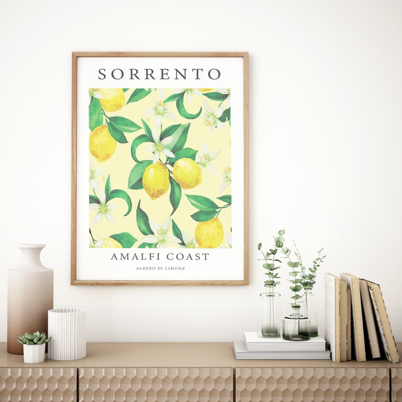 May include: A framed print with a yellow background and a pattern of green leaves, white flowers, and yellow lemons. The text "SORRENTO AMALFI COAST ALBERO DI LIMONE" is printed on the print.
