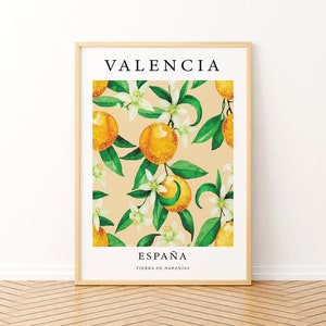 Op de afbeelding: Een ingelijst print met een aquarel-illustratie van sinaasappelbloesems en sinaasappelen op een licht beige achtergrond. De tekst "VALENCIA" staat bovenaan de print en "ESPA&Ntilde;A TIERRA DE NARANJAS" staat onderaan.
