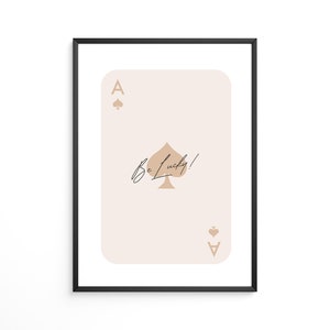 May include: A beige and brown ace of spades playing card with the text "Be Lucky!" printed on it. The card is framed in a black frame.