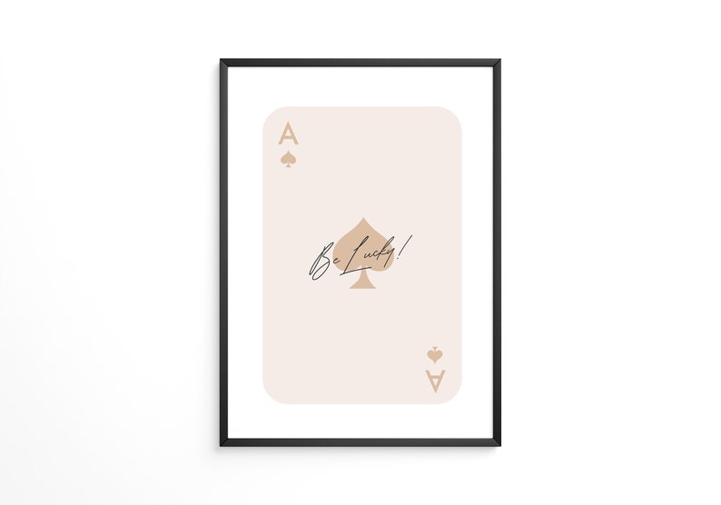 May include: A beige and brown ace of spades playing card with the text "Be Lucky!" printed on it. The card is framed in a black frame.