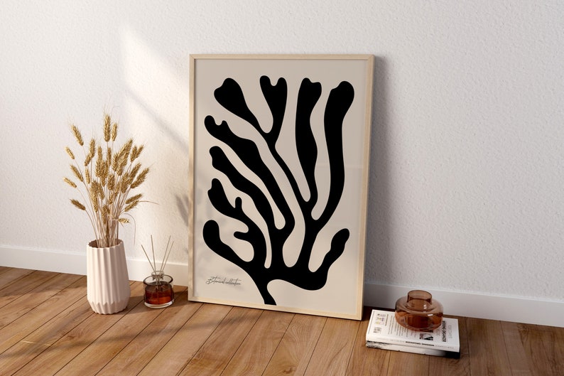 May include: A black and white abstract print of a stylized branch with a beige background. The print is framed in a light wood frame.