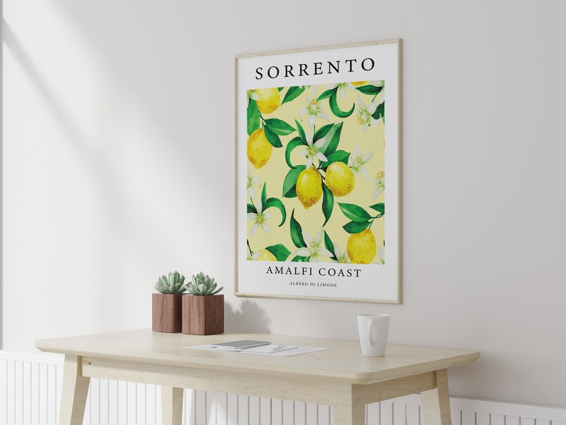 May include: A framed print with a yellow background featuring a watercolor illustration of lemon trees with green leaves and white flowers. The text "SORRENTO AMALFI COAST ALBERI DI LIMONE" is printed below the illustration.