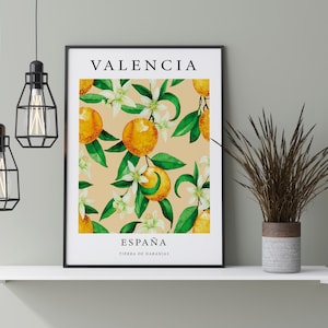 Op de afbeelding: Een ingelijst afdruk met een aquarel-illustratie van sinaasappelbloesems en sinaasappelen. De afdruk bevat de tekst "Valencia, Espa&ntilde;a, Tierra de Naranjas" in zwart.