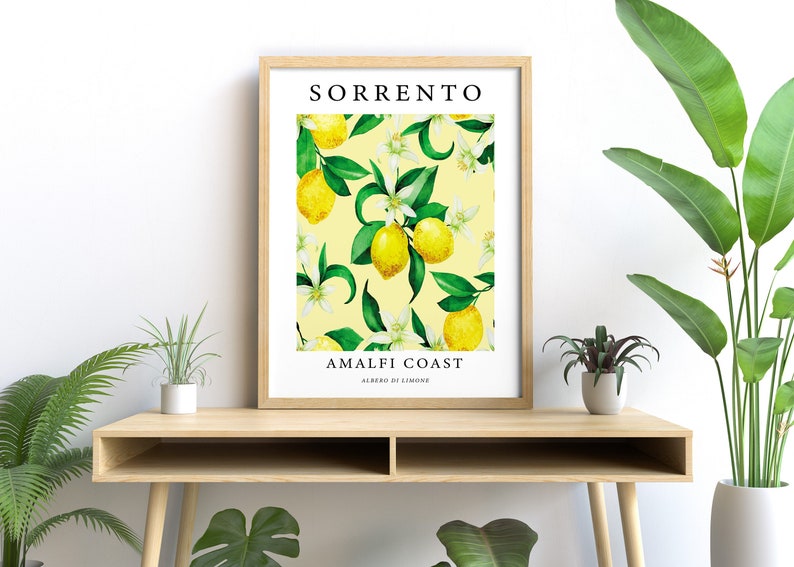 May include: A framed print with a yellow background and a pattern of green leaves, white flowers, and yellow lemons. The text "SORRENTO AMALFI COAST ALBERO DI LIMONE" is printed on the print.