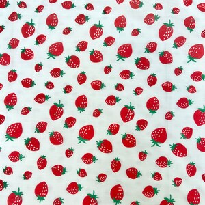 May include: White fabric with a repeating pattern of red strawberries. The strawberries are scattered randomly across the fabric.