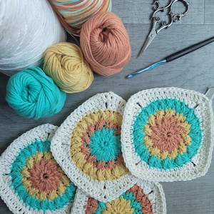 May include: Four crocheted squares in shades of white, teal, yellow, and orange. The squares are arranged in a staggered pattern, with the largest square in the center. There are also balls of yarn in various colors, a crochet hook, and a pair of scissors.