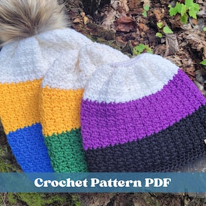 May include: Three crocheted beanies featuring horizontal color-blocked patterns. One hat has a faux fur pom-pom. The hats display white, yellow, blue, green, purple, and black yarn. A small rectangular tag with the text "Riccie's Creations" is attached.