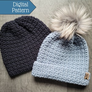 May include: Two crocheted hats, one black and one light blue. The blue hat has a faux fur pom pom on top. The hats are on a woodgrain surface.